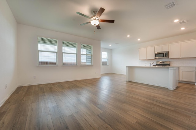 3616 Mallard Way, Mckinney, TX 75071 - kitchen featuring stainless steel microwave, range, open floor plan, ceiling fan, and light wood-style floors