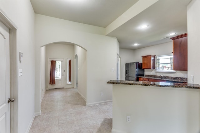 4201 Tower Ln, Crowley, TX 76036 - kitchen with black fridge with ice dispenser, arched walkways, a sink, recessed lighting, and dark stone counters