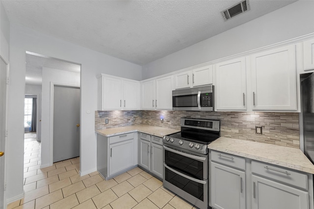 2312 Collier Dr, Mckinney, TX 75071 - kitchen featuring stainless steel appliances, backsplash, light tile patterned floors, white cabinets, and a textured ceiling