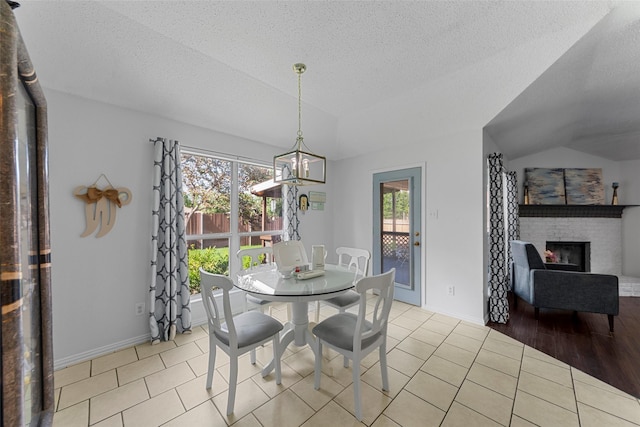 2312 Collier Dr, Mckinney, TX 75071 - dining space with lofted ceiling, plenty of natural light, a textured ceiling, baseboards, and a brick fireplace