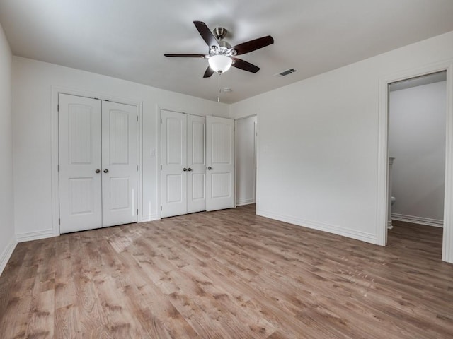 614 Shady Ln, Seagoville, TX 75159 - unfurnished bedroom featuring light wood-style flooring, two closets, baseboards, and a ceiling fan