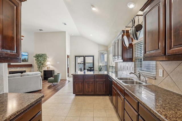 1336 Castlegar Ln, Fort Worth, TX 76247 - kitchen with dark countertops, a sink, lofted ceiling, open floor plan, and a peninsula