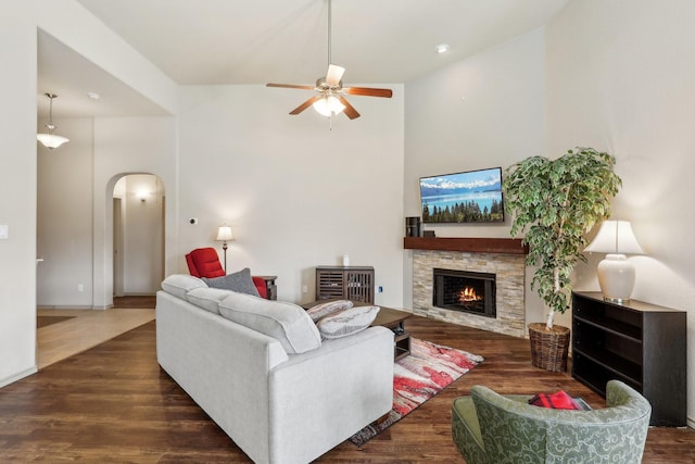 1336 Castlegar Ln, Fort Worth, TX 76247 - living area with arched walkways, a ceiling fan, a high ceiling, a stone fireplace, and wood finished floors