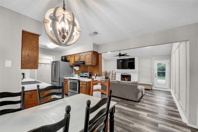 716 Vickie Dr, Azle, TX 76020 - kitchen with stainless steel appliances, brown cabinetry, a chandelier, light countertops, and light wood-style floors