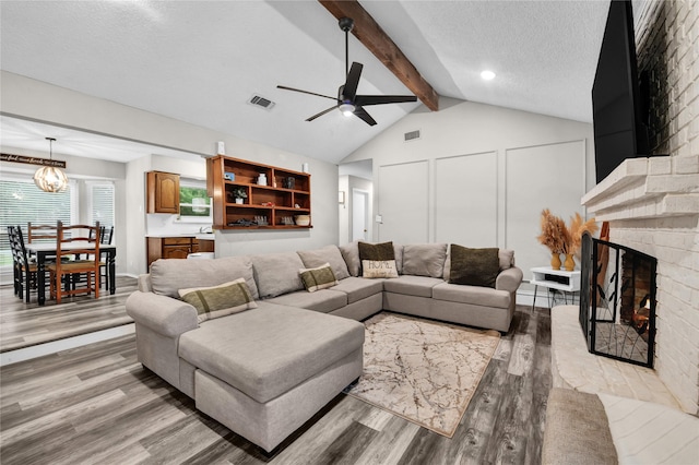 716 Vickie Dr, Azle, TX 76020 - living area featuring light wood-style floors, a ceiling fan, a large fireplace, a textured ceiling, and a chandelier