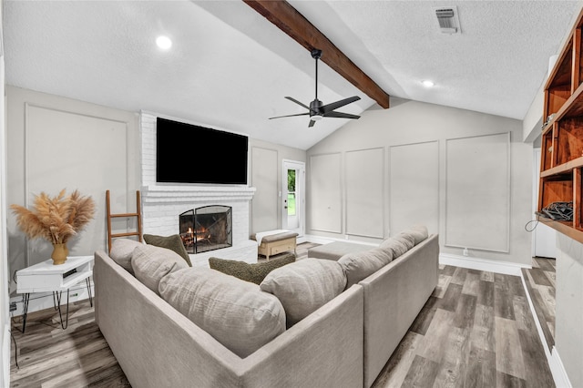 716 Vickie Dr, Azle, TX 76020 - living area featuring a ceiling fan, a fireplace, wood finished floors, a textured ceiling, and a decorative wall