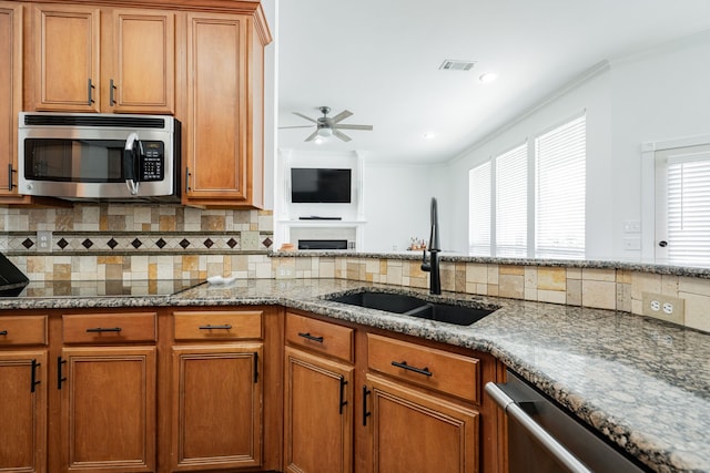 1005 Ruidoso Downs Dr, Talty, TX 75160 - kitchen featuring appliances with stainless steel finishes, decorative backsplash, ceiling fan, brown cabinets, and crown molding