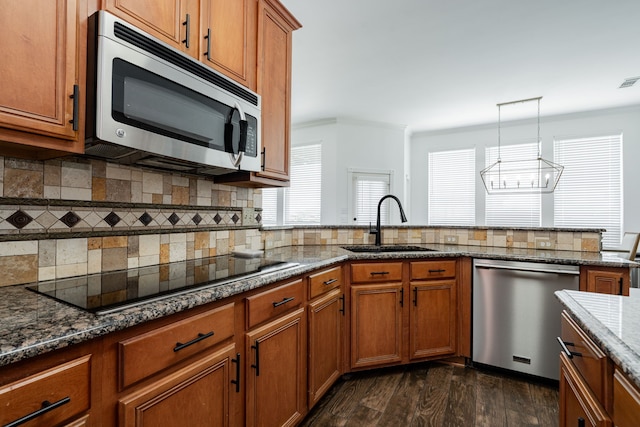 1005 Ruidoso Downs Dr, Talty, TX 75160 - kitchen with appliances with stainless steel finishes, brown cabinetry, tasteful backsplash, dark stone countertops, and a chandelier