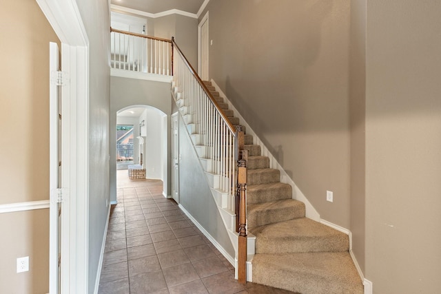 1908 Canyon Wren Dr, Mckinney, TX 75071 - stairway with arched walkways, baseboards, tile patterned flooring, a towering ceiling, and ornamental molding
