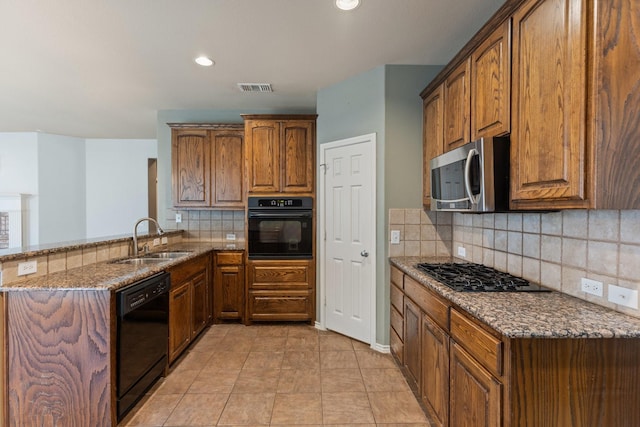 1908 Canyon Wren Dr, Mckinney, TX 75071 - kitchen featuring black appliances, a sink, dark stone countertops, backsplash, and brown cabinetry