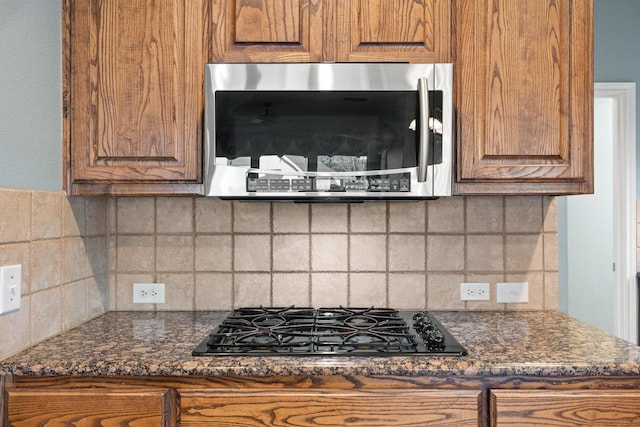 1908 Canyon Wren Dr, Mckinney, TX 75071 - kitchen with stainless steel microwave, black gas stovetop, brown cabinetry, and tasteful backsplash