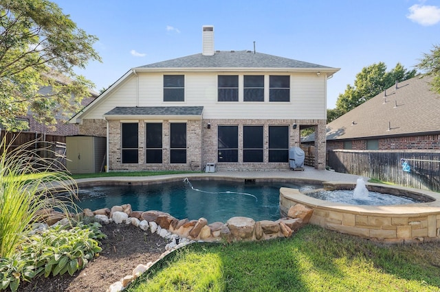 1908 Canyon Wren Dr, Mckinney, TX 75071 - back of property with a fenced backyard, a chimney, a pool with connected hot tub, roof with shingles, and brick siding
