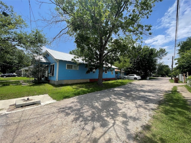 1206 Walnut St, Greenville, TX 75401 - view of side of property featuring a metal roof, a lawn, and driveway