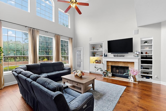 4700 Scoter Ln, Mckinney, TX 75072 - living area featuring a high ceiling, ceiling fan, built in shelves, wood finished floors, and a fireplace with flush hearth