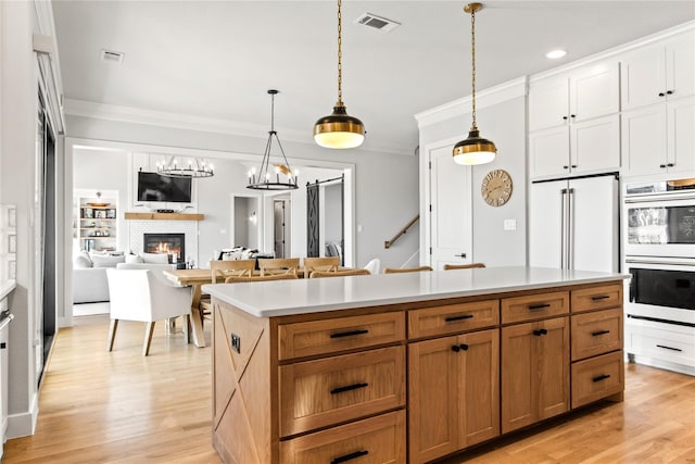 200 Sutherland Cres, Northlake, TX 76247 - kitchen with white double oven, ornamental molding, pendant lighting, a fireplace, and light wood-style floors