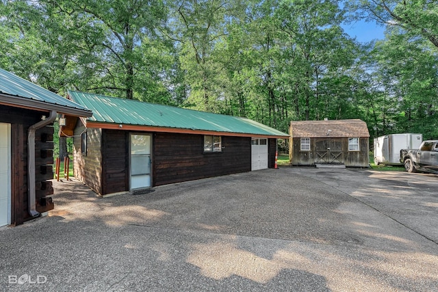 250 Mayo Rd, Shreveport, LA 71106 - view of home's exterior featuring a garage, driveway, metal roof, and view of wooded area