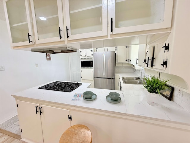 1136 Simpson Dr, Hurst, TX 76053 - kitchen with freestanding refrigerator, built in microwave, black gas cooktop, a peninsula, and decorative backsplash