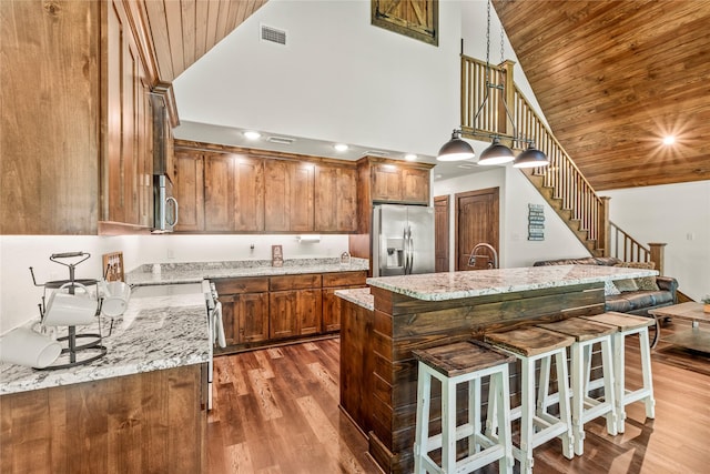 102 Anderson Ln, Mabank, TX 75156 - kitchen featuring stainless steel appliances, wood ceiling, high vaulted ceiling, brown cabinets, and a kitchen bar