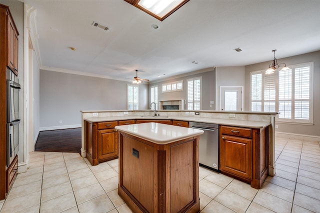 2673 April Sound Ln, Frisco, TX 75033 - kitchen with stainless steel appliances, a center island, a sink, brown cabinetry, and a ceiling fan