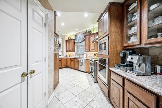 3820 Nash Ln, Plano, TX 75025 - kitchen featuring stainless steel appliances, backsplash, wall chimney exhaust hood, brown cabinets, and glass insert cabinets