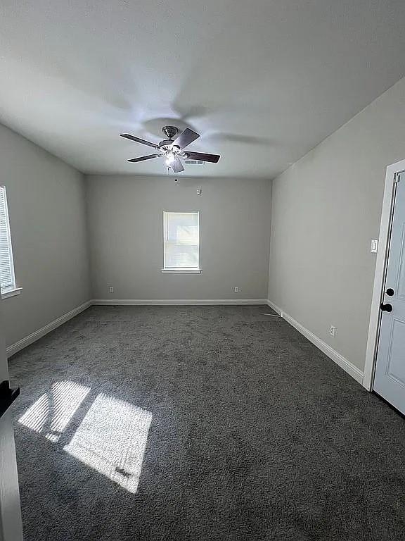1633 Stoneman, Dallas, TX 75215 - spare room featuring dark colored carpet, ceiling fan, and baseboards