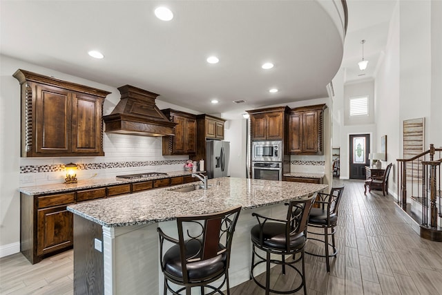 3300 Calvin Rd, Mckinney, TX 75071 - kitchen with appliances with stainless steel finishes, a sink, premium range hood, tasteful backsplash, and a breakfast bar