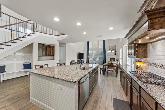3300 Calvin Rd, Mckinney, TX 75071 - kitchen with appliances with stainless steel finishes, open floor plan, light wood finished floors, a sink, and a fireplace