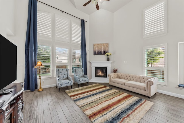 3300 Calvin Rd, Mckinney, TX 75071 - living area with high vaulted ceiling, a ceiling fan, a glass covered fireplace, wood finished floors, and baseboards