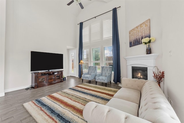 3300 Calvin Rd, Mckinney, TX 75071 - living area featuring a towering ceiling, ceiling fan, wood finished floors, a glass covered fireplace, and baseboards