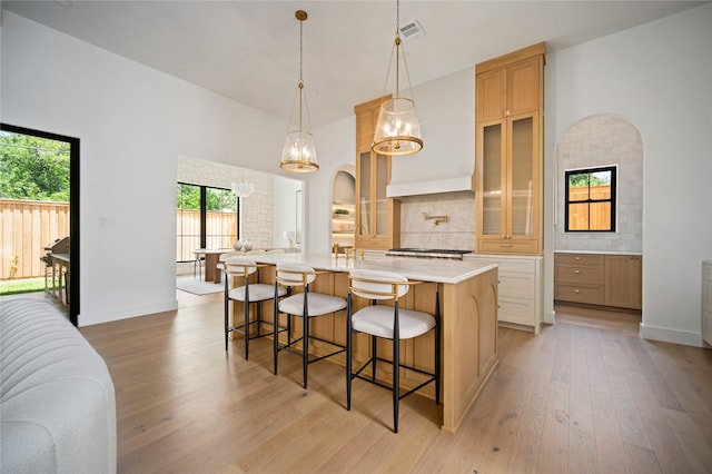 3727 Clover Ln, Dallas, TX 75220 - kitchen featuring light countertops, a kitchen breakfast bar, glass insert cabinets, a large island with sink, and backsplash