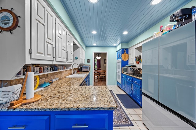 907 Green Terrace Ln, Duncanville, TX 75137 - kitchen with recessed lighting, refrigerator, white cabinetry, blue cabinets, and light stone countertops