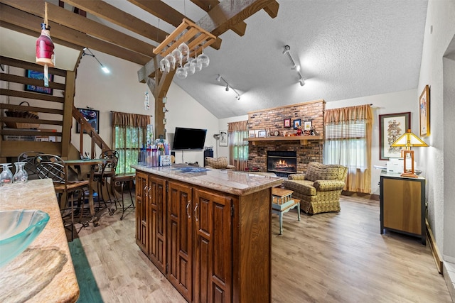 907 Green Terrace Ln, Duncanville, TX 75137 - kitchen featuring open floor plan, light countertops, a fireplace, light wood-style flooring, and lofted ceiling