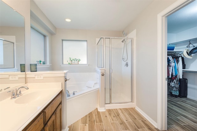 102 Avery Ln, Fate, TX 75189 - bathroom with wood finish floors, a garden tub, vanity, a stall shower, and a walk in closet