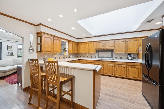 1533 Aylesbury Ln, Plano, TX 75075 - kitchen with black appliances, crown molding, a skylight, a peninsula, and light wood-type flooring