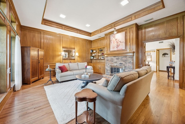 1533 Aylesbury Ln, Plano, TX 75075 - living room featuring a tray ceiling, wood walls, a brick fireplace, light wood-style floors, and crown molding