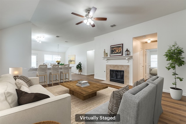 2704 Calmwater Dr, Little Elm, TX 75068 - living area with vaulted ceiling, wood finished floors, a tiled fireplace, a ceiling fan, and baseboards