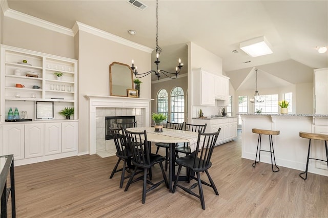 7816 Blossom Dr, Fort Worth, TX 76133 - dining space with a chandelier, a tile fireplace, light wood-style floors, crown molding, and lofted ceiling
