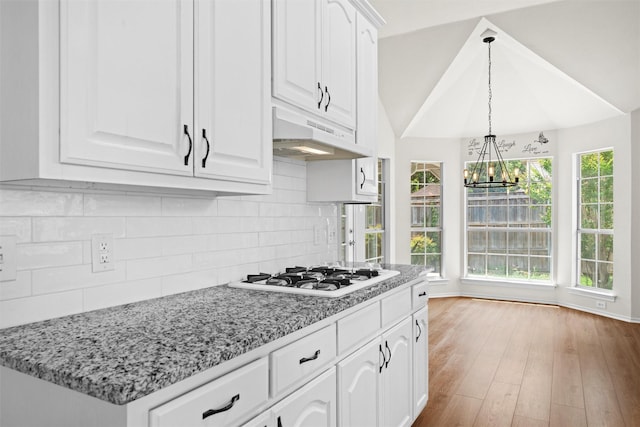 7816 Blossom Dr, Fort Worth, TX 76133 - kitchen featuring under cabinet range hood, white gas cooktop, a chandelier, white cabinets, and backsplash