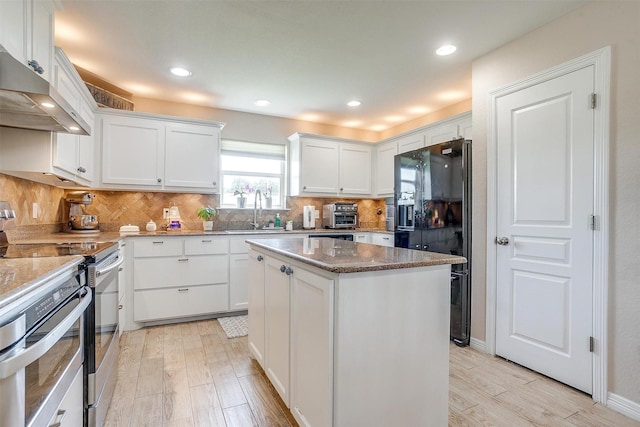 112 Tigers Eye Ct, Weatherford, TX 76087 - kitchen with stainless steel range with electric cooktop, a sink, black fridge, range hood, and light wood finished floors