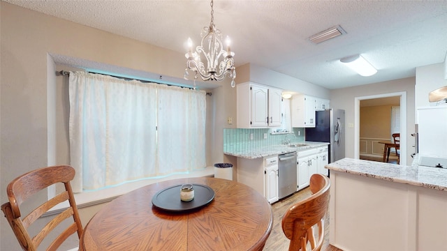 1931 Crestside Cir, Carrollton, TX 75007 - kitchen with appliances with stainless steel finishes, white cabinets, a textured ceiling, decorative backsplash, and a chandelier