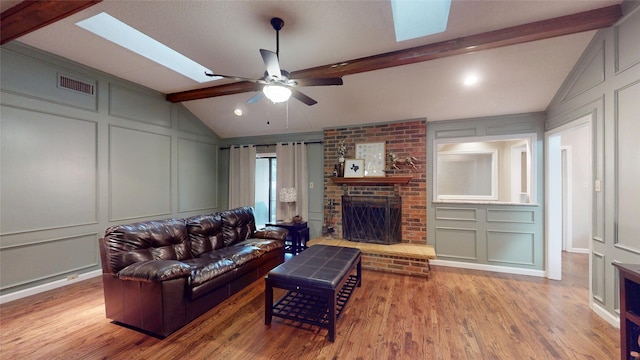 1931 Crestside Cir, Carrollton, TX 75007 - living area with a decorative wall, a skylight, wood finished floors, a brick fireplace, and a ceiling fan