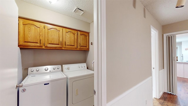 1931 Crestside Cir, Carrollton, TX 75007 - laundry area featuring separate washer and dryer, a textured ceiling, cabinet space, and light wood-style flooring