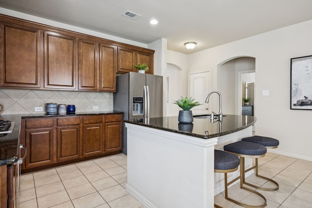 8100 Delaware Dr, Mckinney, TX 75070 - kitchen featuring a sink, arched walkways, stainless steel refrigerator with ice dispenser, light tile patterned floors, and tasteful backsplash