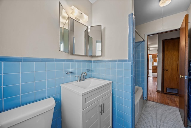 3212 Medina Ave, Fort Worth, TX 76133 - bathroom featuring tile walls, toilet, vanity, washtub / shower combination, and wainscoting