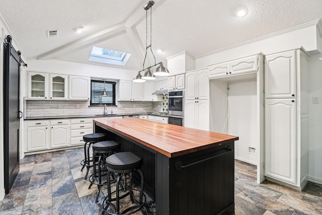 1510 Waltham Ct, Arlington, TX 76012 - kitchen with butcher block counters, a sink, a skylight, a textured ceiling, and white cabinetry