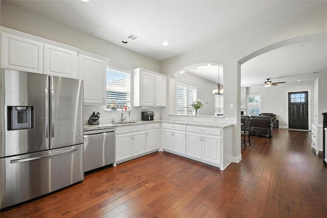 7514 Harbor Dr, Rowlett, TX 75088 - kitchen featuring stainless steel appliances, arched walkways, a ceiling fan, tasteful backsplash, and a peninsula