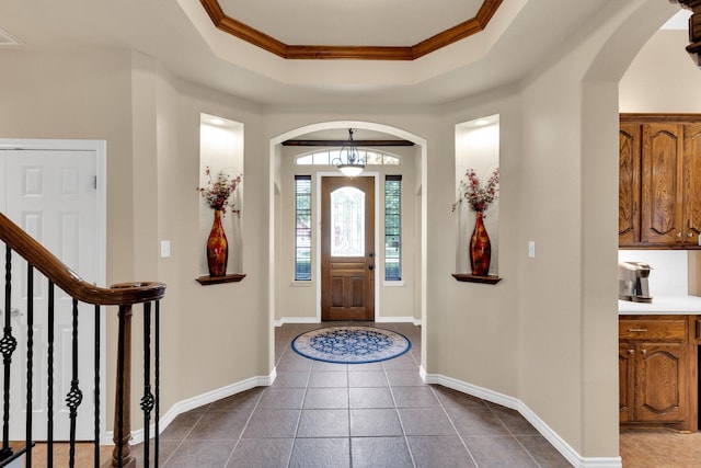 5210 Medallion Ct, Midlothian, TX 76065 - foyer entrance featuring arched walkways, ornamental molding, a tray ceiling, dark tile patterned flooring, and baseboards