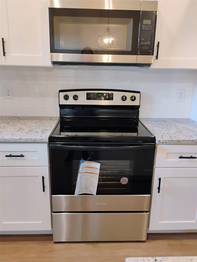 901 SW 10th St, Mineral Wells, TX 76067 - kitchen with stainless steel appliances, white cabinetry, backsplash, and light wood finished floors