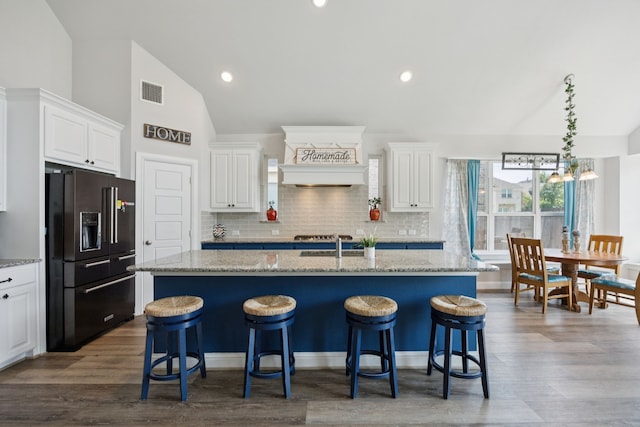1305 Mary Horn Ln, Aubrey, TX 76227 - kitchen with black refrigerator with ice dispenser, vaulted ceiling, white cabinetry, backsplash, and a kitchen bar