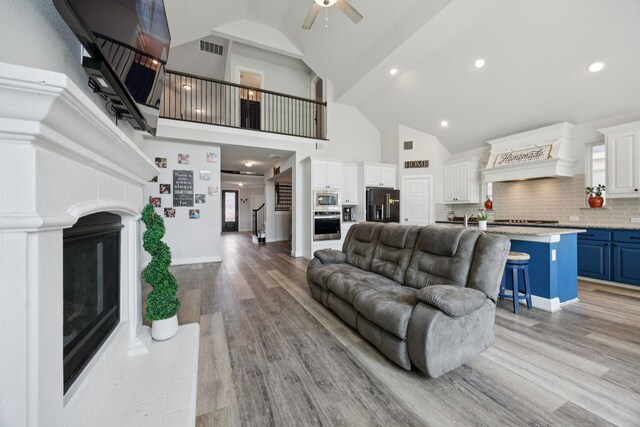 1305 Mary Horn Ln, Aubrey, TX 76227 - living area with ceiling fan, a fireplace, light wood-type flooring, high vaulted ceiling, and recessed lighting